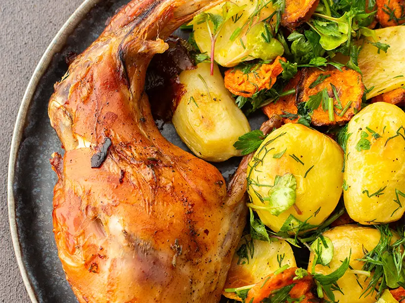 Pezzi di coniglio arrosto in una casseruola con erbe aromatiche