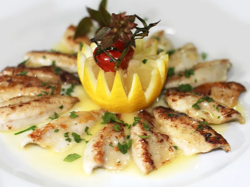 Filets de perches dorés servis avec des frites allumettes et un quartier de citron